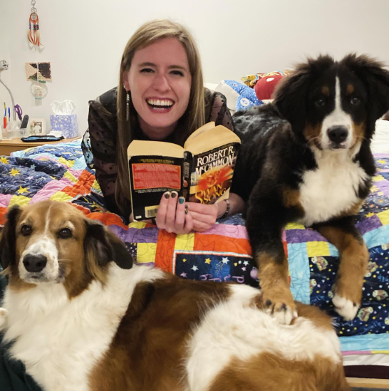 Women sitting with book and 2 dogs